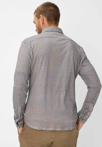 Camicia con bottoni in un motivo a quadri blu e marrone, con maniche lunghe, colletto e orlo curvo, realizzata in cotone leggero.