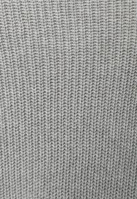 Světle šedá pletenina s texturovaným vzorem, který obsahuje svislé žebrování a měkký povrch, vhodná pro oděvy nebo doplňky.