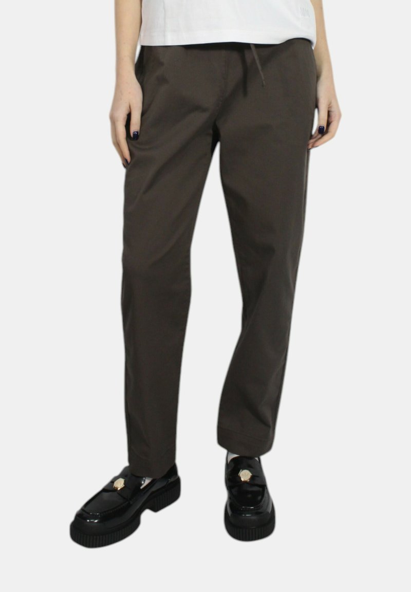 Pantaloni marroni, leggeri, a gamba dritta con vita elastica e cordoncino. Abbinati a mocassini neri, spessi, con un accento dorato.