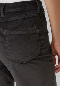 Pantalon en velours côtelé gris avec des côtes verticales, une poche arrière avec un contour cousu et un accent métallique près de la taille.