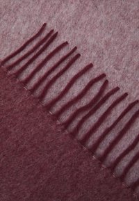 Écharpe en laine bordeaux et gris clair avec une surface douce et texturée, ornée de franges le long d'un bord.