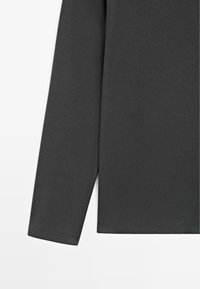 Donkergrijs shirt met lange mouwen, gemaakt van zacht materiaal; heeft een rechte zoom en eenvoudige manchetten met minimale details.