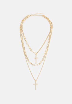 Collier chaîne en or à trois couches avec deux pendentifs croix, présentant un mélange de maillons fins et épais.