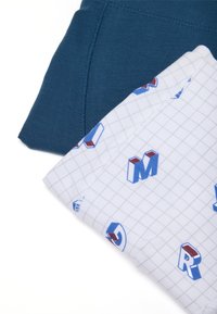 Due abiti: una maglietta a maniche corte di un verde scuro con texture a coste e una camicia bianca a motivi con lettere multicolori su una griglia.