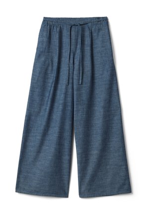 Weit geschnittene blaue Leinenhose mit elastischem Bund und vorderem Kordelzug, flach auf weißem Hintergrund liegend.