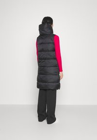 Czarna pikowana długa kamizelka z wysokim kołnierzem i eleganckim krojem, wyposażona w poziome przeszycia i boczne rozcięcia dla ułatwienia ruchów.