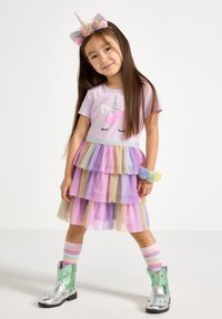 Enhörningstema klänning med en lila topp och en lager-på-lager pastellfärgad tyllkjol. Tillbehör inkluderar en blomsterkrans och silverfärgade cowboystövlar.