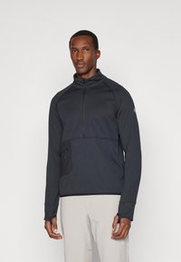 Veste pullover noire à zip quart en tissu texturé, col haut, manches longues et poche avant en biais. Design simple et moderne.