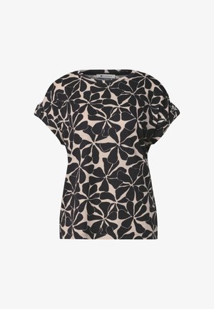 Chemise beige à manches courtes avec grand motif abstrait de feuilles noires et manches retroussées maintenues par des boutons.