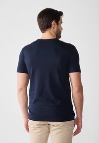 Navy blåt kortærmet t-shirt i et blødt, strækbart stof med en klassisk rund hals og en lige pasform, set bagfra.