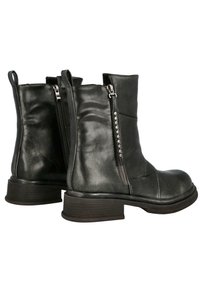 Botas de tobillo de cuero negro con una textura suave, cremallera lateral y un tacón bajo en bloque. Cuenta con costuras sutiles y adornos metálicos decorativos.