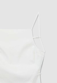 Top bianco senza maniche con spalline sottili regolabili su uno sfondo grigio chiaro.