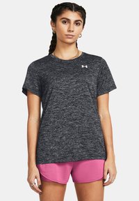 Grå melert atletisk t-skjorte med korte ermer og rund hals. Har en liten hvit logo på venstre bryst og er kombinert med rosa shorts.