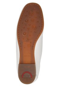 Weiße Schuhsohle mit kreisförmigen Texturmuster, braunem Gummi-Material und rotem Branding-Akzent in der Nähe der Ferse. Glattes Kantendesign.