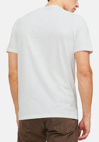 Hvid kortærmet T-shirt med rund hals, lavet af blødt stof, vist fra ryggen, med et ensfarvet design uden mønstre.