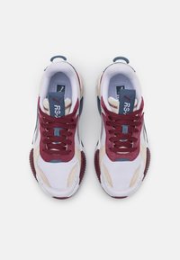 Białe sneakersy z akcentami w kolorach bordowym, niebieskim i beżowym. Materiał o fakturze, okrągły nosek i płaskie sznurowadła. Marka PUMA na języku i boku buta.