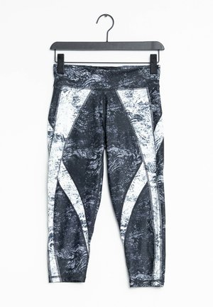 Leggings a motivi in bianco e nero con un design testurizzato, accentuati da dettagli bianchi a contrasto e un'ampia vita, appesi a un gancio.