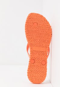 Orange flip-flop sole with textured braided pattern and embossed brand name, showing size US 7, EUR 37, UK 4.