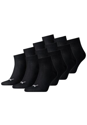 Schwarze Knöchelsocken, die in einem Stapel angeordnet sind. Mit einem gerippten Bündchen und einem kleinen weißen Logo an der Seite. Aus weichem Stoff gefertigt. Im Pack mit zehn Socken.