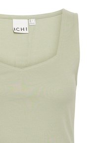 Haut sans manches côtelé vert clair avec encolure carrée et étiquette de marque visible à l'intérieur du col indiquant la taille small.