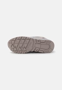 Shoe outsole with a textured gray rubber surface, featuring a multi-directional tread pattern and embossed brand logo.