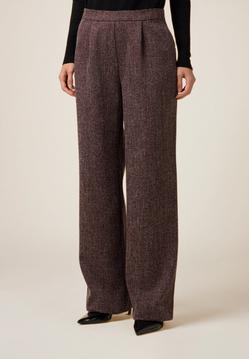 Spodnie o szerokich nogawkach z bordowego materiału o teksturowanym wykończeniu. Posiadają wysoki pas i przednie zakładki. W zestawieniu z czarnymi szpilkami o zaostrzonych noskach.