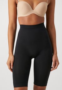 Black high-waisted shapewear shorts made from a smooth, stretchy material, featuring a mid-thigh length and a seamless design.