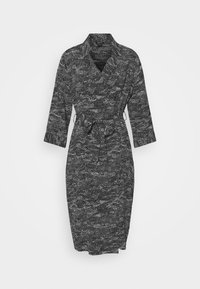 Svart- och vitmönstrad klänning med krage, långa ärmar, bälte i midjan och knälång kjol. Tillverkad av ett strukturerat tyg.