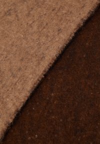 Tissu en feutre brun et beige, présentant une texture douce et une apparence naturelle avec de subtiles variations de fibres et un contour organique.