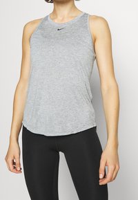 Grå atletisk tanktop med rund hals og ærmeløs design. Har Nike-logoen i sort i midten. Blødt, åndbart stof.