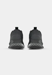 Crne Nike tenisice s teksturiranim mrežastim gornjištem, povlačnim trakama i gumiranim potplatom s složenim uzorkom đona. Elegantni, minimalistički dizajn.