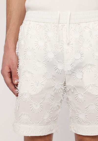 Hvide shorts lavet af bomuld, med tekstureret broderi i cirkulære mønstre og frynseaccenter, elastisk talje og snor.