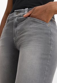 Graue Jeans aus Denim im Slim-Fit mit einem kleinen Knopfverschluss, Fronttasche und dezenter Verblassung in der Stoffstruktur.