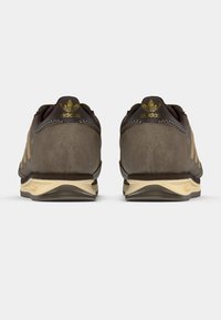 Rjavi semiš supergi z bež poudarki, z oblazinjeno podplatom, teksturiranim šivom in zlatim logotipom na peti.