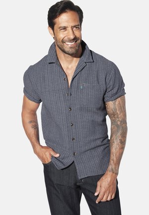 Short-sleeve, button-up shirt in navy with a small geometric pattern. Features a chest pocket and brown buttons. Textured fabric.