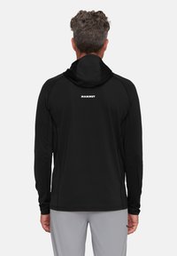 Sort hoodie med lange ærmer, hætte, elastiske manchetter og et elegant design. Har et synligt hvidt "Mammut" logo på ryggen.