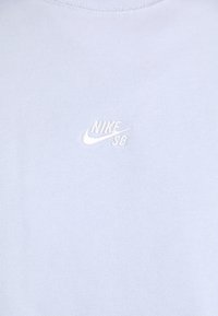 Light blue T-shirt made from soft cotton. Features a small white embroidered Nike SB logo on the chest. Round neckline, no additional patterns.