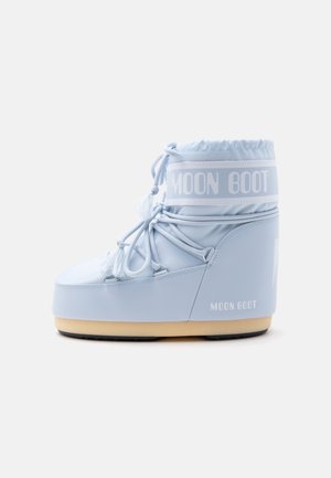 Moon Boot bleu clair avec cheville haute rembourrée, laçage frontal et semelle beige, présenté de côté sur fond blanc.