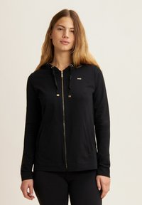 Felpa nera con zip, dotata di dettagli in oro, cordini regolabili, maniche lunghe e tasche frontali, realizzata in un materiale morbido e elastico.