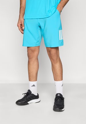 Turkooizen sportshort met een wit logo met drie strepen aan de linkerkant. Draagt zwarte sneakers en witte enkelsokken. Gladde textuur.