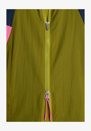 Grüne Jacke mit Reißverschluss, silbernem Zipper und pinkfarbenen Zugschnüren, zeigt strukturierten Stoff und Teile von dunklen und pinkfarbenen Ärmeln.