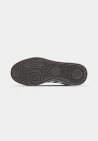 Semelle de chaussure en caoutchouc noir avec un motif de traction complexe, comportant des designs circulaires et linéaires. Le bord est légèrement arrondi pour le confort.
