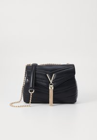 Black leather handbag with quilted design, gold chain strap, and metal V-shaped accent with tassel detail. Compact rectangular shape.
