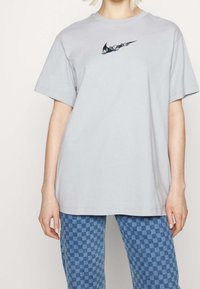 Grå bomulls t-shirt med rund halsringning och korta ärmar, med svart och blommig broderad logotyp på framsidan.