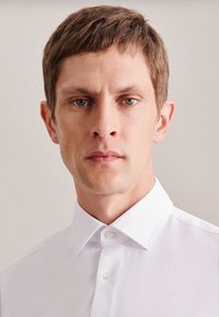 Witte coll shirt met een gladde textuur, klassieke knoopsluiting en een gestructureerde kraag. Eenvoudig ontwerp zonder patronen of accenten.