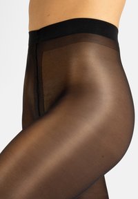 Pantys negros semitransparentes con un acabado mate suave. Presentan una cinturilla opaca amplia y una pierna semi-translúcida para una apariencia elegante.