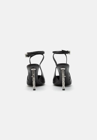 Sandalias negras de tacón con la parte trasera abierta y correa en el tobillo, con un tacón texturizado brillante y un patrón decorativo.
