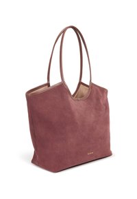 Sac fourre-tout en daim couleur rose poudré, avec une texture douce, deux longues anses et un design minimaliste. Présente un logo discret en or sur le côté.