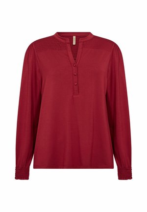 Red long-sleeve blouse with a mandarin collar, three-button placket, smocked detailing on shoulders, and gathered cuffs. Soft fabric texture.