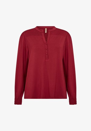 Rote Bluse mit langen Ärmeln und Stehkragen, Dreiknopfverschluss, Raffung an den Schultern und gepufften Bündchen. Weiche Stofftextur.